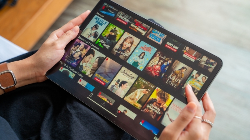 Osoba drži tablet sa otvorenom Netflix aplikacijom i prikazom filmskih naslova